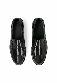 Mocasines de charol negro con un acabado suave, detalles cosidos y un diseño cómodo de calce fácil. Suela plana con puntera redondeada.