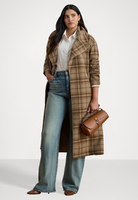 Cappotto lungo a quadri marrone, camicia bianca, jeans a vita alta blu a gamba larga, borsa in pelle marrone e scarpe basse marroni. Tessuti lisci e vestibilità su misura.