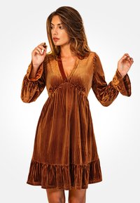 Vestido de terciopelo marrón con rayas verticales, escote en V profundo, mangas largas acampanadas y un dobladillo con volantes. Textura suave con un ligero brillo.