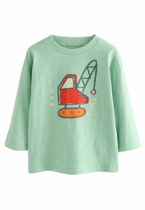 Camicia di cotone verde con maniche lunghe, caratterizzata da una grafica di un escavatore rosso e il testo "DIVERTIMENTO" in arancione. Tessuto morbido e vestibilità rilassata.