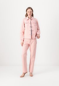Light pink denim jacket with button closure and pockets, paired with matching light pink trousers. Smooth texture, casual fit, and simple design.