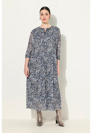 Maxi dress in lightweight, sheer fabric featuring a blue and gray leopard print, three-quarter sleeves, and a round neckline. Silver ankle boots.