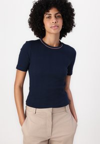 Cămașă navy cu mânecă scurtă, cu guler rotund și trim contrastant. Cămașa are o siluetă ajustată și este fabricată dintr-un material neted.