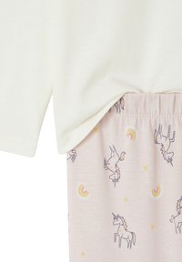 Light pink elastic waistband pants with unicorn, rainbow, star, and cloud patterns paired with an off-white long-sleeve top.