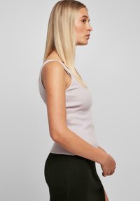 Lichtpaarse geribde tanktop met smalle banden, aansluitend design en zachte textuur, gecombineerd met een donkergroene aansluitende rok.