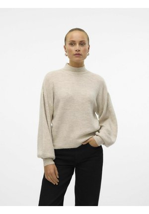 Light beige sweater with a high neck and dropped shoulders, featuring wide sleeves and a soft texture, paired with black trousers.
