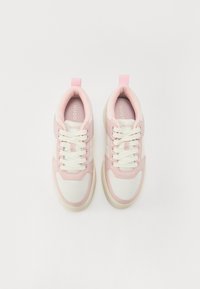 Roosid ja valged värvid sneakersid, millel on kangas ülemine osa, pehmendustega kaelaosa ja valged paelad. Bränding on nähtav keele peal.