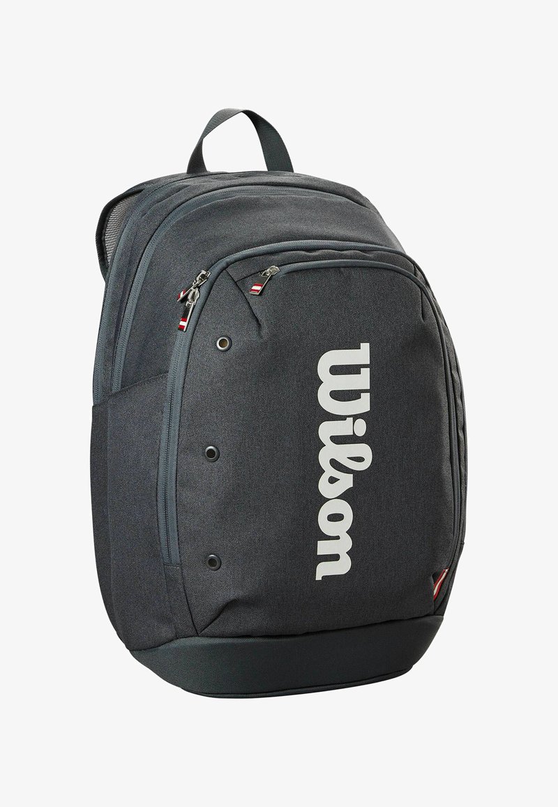 Grijze stoffen rugzak met een groot wit "Wilson" logo. Bevat meerdere met rits afgesloten vakken en een handvat aan de bovenkant. Gestructureerd oppervlak.