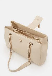 Beige synthetische Handtasche mit einer strukturierten Oberfläche, ausgestattet mit goldfarbenen Beschlägen, doppelten Ketten- und Tragegriffen sowie einer durch einen Reißverschluss verschlossenen Innentasche.