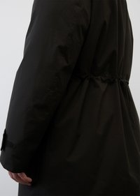 Schwarze Oberbekleidung aus strukturiertem Stoff, mit taillierter Taille und Klettverschlussdetail an den Ärmeln. Entworfen mit einer lockeren Passform und schlanker Silhouette.