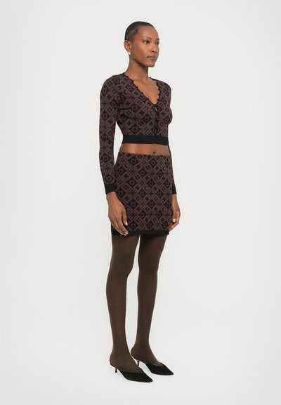 Knitted set featuring a long-sleeve top and mini skirt in dark maroon with geometric patterns, textured detailing, and a fitted silhouette.