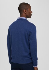 Maglione blu in morbido intreccio con colletto rotondo, polsini con strisce bianche e blu navy, e design aderente. Texture liscia con orlo a coste.