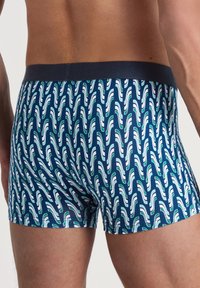Marineblauwe boxershort met een golvenpatroon in het wit en groen. Elastische tailleband, gladde stof, aansluitend ontwerp.