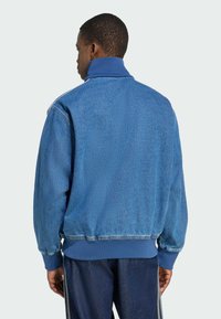 Denimjacke in Mitteltönen mit strukturierter Oberfläche, gerippten Bündchen und Saum sowie hohem Kragen. Mit weißen Schulterstreifen und lockerer Passform.