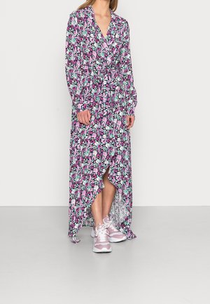 Maxi kjole med lange ærmer, blomsterprint i pink og grøn på sort baggrund, indsnævret talje og høj-lav kant. Parret med pink sneakers.