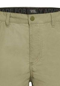 Lys beige shorts i blødt, let materiale, med knaplukning og en mærket talje med "Camel Active" tekst.