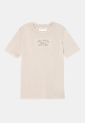 Lysebeige t-shirt med korte ærmer og rund hals med teksten "Abercrombie & Fitch New York" centreret på brystet i en lidt mørkere nuance.
