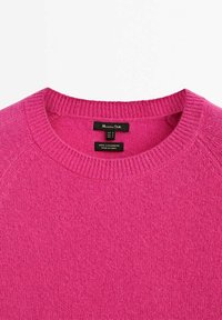 Pull en cachemire fuchsia avec un col rond côtelé et un tissu légèrement texturé. Étiquette visible indiquant 100 % cachemire, fabriqué en Chine.