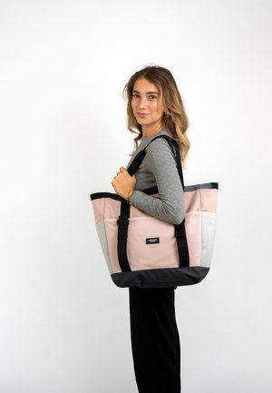 Bolso de lona con un diseño en bloques de color rosa, gris y negro. Cuenta con dos asas negras y un pequeño logo en la parte frontal. Forma rectangular.