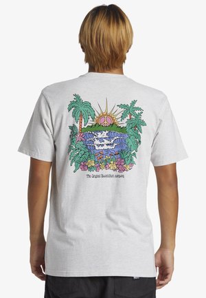 Persoon draagt een lichtgrijs T-shirt met een kleurrijk tropisch ontwerp met golven, palmbomen, bloemen en een zon met een vredessymbool.