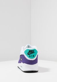 Baskets Nike Air Max avec une tige en mesh blanc, un accent violet, un panneau latéral noir et un passant de talon turquoise avec logo. Semelle extérieure en caoutchouc, design amorti.