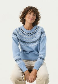 Light blue knitted sweater featuring a round neckline and intricate black and white patterns around the chest and sleeves.