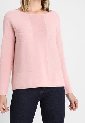 Jersey rosa acanalado con escote cuadrado, mangas largas y detalles con panel texturizado en la parte delantera. Combinado con jeans oscuros.