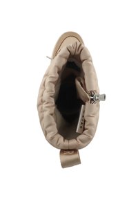 Bolsa de drawstring beige con un forro de piel sintética, que cuenta con una cremallera plateada y una etiqueta en el interior. El exterior es suave con una textura blanda.