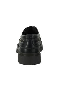 Black leather shoes with a rounded toe and flat sole. Notable gold hardware accents and stitched detailing on the back and sides.