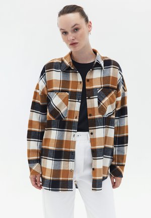 Flannel shirt with a plaid pattern in orange, white, and navy. Features two chest pockets, a button-up front, and long sleeves.