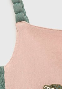 Katoenen tas van een mengsel met een lichtroze lichaam en een groene gestructureerde strap. Bevat een geborduurd detail in groen en wit aan de onderkant.