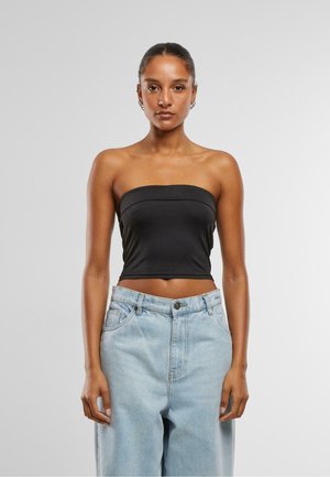 Top nero senza spalline con design aderente, texture liscia e dettagli di cucitura discreti, abbinato a jeans in denim a vita alta di colore azzurro chiaro.