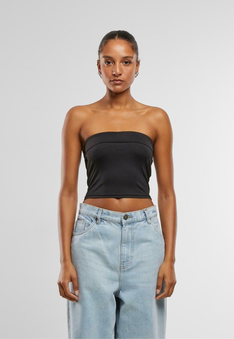 Top negru fără bretele, cu un design ajustat, textură netedă și detalii subtile ale cusăturii, purtat cu blugi din denim deschiși, cu talie înaltă.