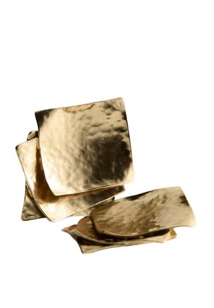Pile de six plaques métalliques dorées brillantes et texturées de forme carrée qui se chevauchent sur un fond blanc.