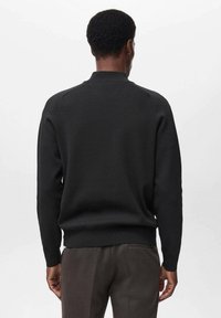 Maglione nero a maglia con collo a giro, polsini e orlo a costine, caratterizzato da una texture liscia e una vestibilità slim, visto di spalle.