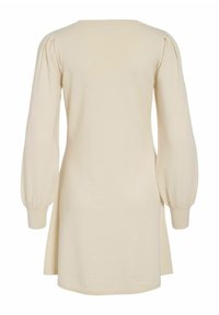 Robe de couleur crème avec un col rond, de longues manches bouffantes et une coupe décontractée. Fabriquée en tissu doux et texturé avec des fentes sur les côtés.