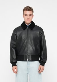Fekete bőrbomber dzseki puha fekete prém gallérral, cipzáros záródással, bordás fekete mandzsettákkal és hempergető aljjal, valamint két oldalsó zsebbel. Simább textúra.