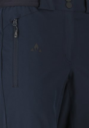 Dunkelblaue Hose mit Reißverschlusstasche an der Seite und kleinem dreieckigem Logo in der Nähe der Tasche am Oberschenkel.