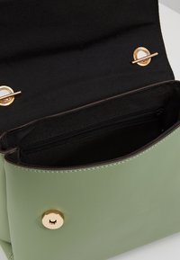 Borsa in ecopelle verde con chiusura a scatto dorata e interno foderato in tessuto nero con una tasca zippata.