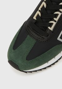 Fekete és zöld sneaker, velúr és hálós anyagokból, kerek orral, fűzővel, fehér középtalppal és texturált fekete talppal.