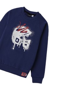 Felpa blu navy con grafica di un casco da football in stile spray paint bianco e rosso e un'etichetta cucita vicino all'orlo inferiore.