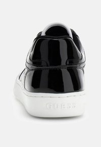 Czarny lakierowany sneaker z białą podeszwą i subtelnymi detalami przeszyć. Logo marki wytłoczone na pięcie. Lekko zaokrąglony fason.