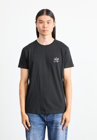 T-shirt din bumbac negru cu mâneci scurte, având un mic logo colorat "ALPHA" pe partea stângă a pieptului și un design clasic de guler rotund.