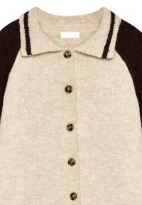 Bež pletena jakna s ovratnikom, rjavi raglan rokavi, šest rjavih gumbov in temne črte na ramenskem delu. Mehak material.