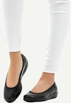 Sorte læder balletflade sko med rund tå, lav kilehælkonstruktion og glat overflade, parret med hvide cropped jeans med frynset kant.