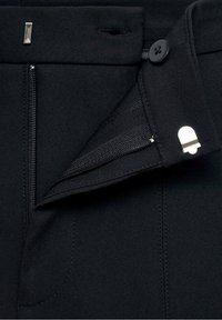 Czarne spodnie wykonane z gładkiego materiału, z zapięciem na suwak, guzikiem i detalem w pasie. Wyraźny wzór ściegów wzdłuż szwów.