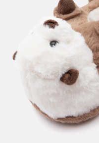 Μαλακό μαξιλάρι σε σχήμα ζώου, με καφέ και λευκό χρώμα, που διαθέτει απαλή υφή, στρογγυλό σχήμα και μικρά μαύρα μάτια. Διακριτικές λεπτομέρειες στα αυτιά και τα πόδια.