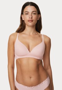 Brahino rosa chiaro realizzato in tessuto liscio con un design a scollatura profonda, spalline sottili regolabili e un delicato pizzo lungo il bordo.