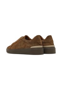 Sneaker in suede marrone con punta rotonda e chiusura con lacci. Presenta una superficie texture e una suola in gomma scura a contrasto.