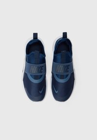 Baskets Nike bleues à enfiler avec une tige en tissu texturé, strap élastique avec logo et semelle en caoutchouc blanche. Sans lacets, faciles à porter.